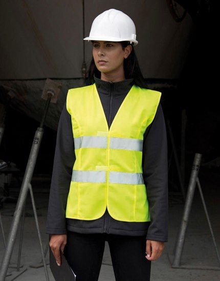 Femme portant un gilet de sécurité jaune fluo haute visibilité et un casque sur un chantier
