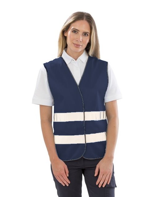Gilet R200 bleu marine personnalisable dès 1 pièce Femme portant un gilet R200 bleu marine à 2 bandes réfléchissantes et fermeture velcro par-dessus un polo blanc