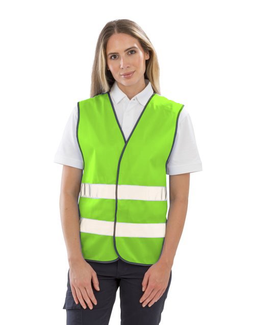 Gilet R200 vert lime personnalisable dès 1 pièce Femme portant un gilet R200 vert lime à 2 bandes réfléchissantes et fermeture velcro par-dessus un polo blanc
